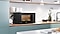 Shows the microwave oven on a kitchen worktop, surrounded by various kitchenware.